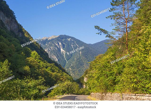 Asphalt road by mountains on the sides, natural light, Abkhazia, Caucasus mountains