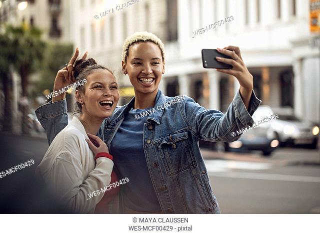 Two carefree young women taking a selfie in the city