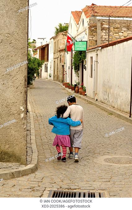 Boy and girl walking in old street with arms around each other, Bozcaada, Turkey