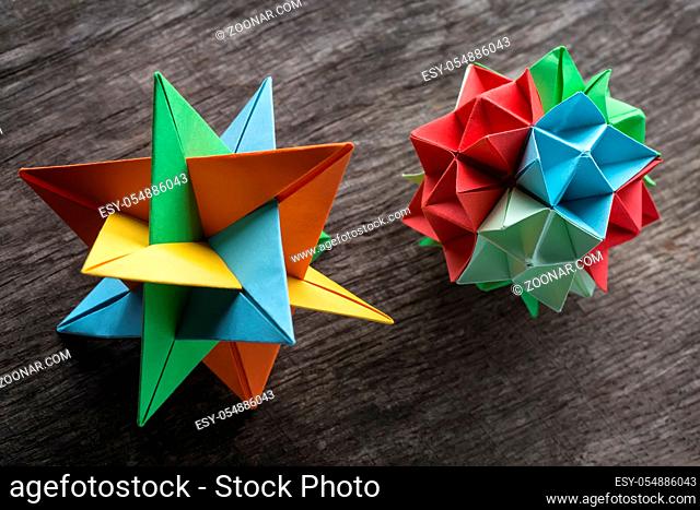 Star and flower kusudama origami on the textured surface. Star origami colored in green, blue, yellow and orange. Flower origami colored in green, red and blue