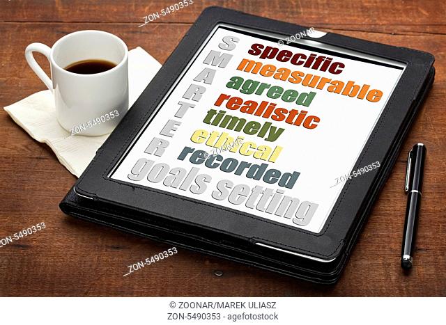 SMARTER (specific, measurable, agreed, realistic, timely, ehtical, recorded) goal setting concept on a digital tablet computer with espresso coffee
