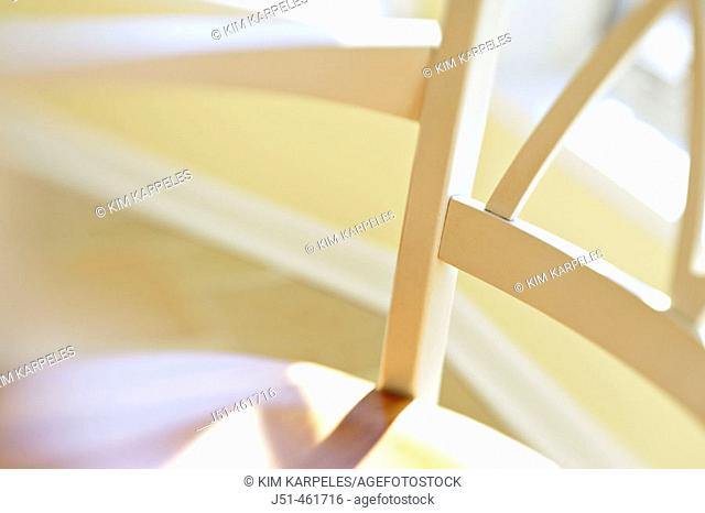 White wooden chair back, seat and arm, window behind in eating area, abstract view with selective focus and blur