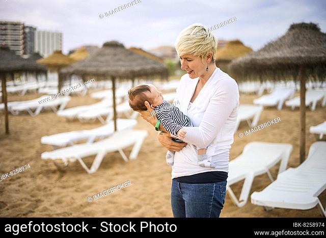 Mother with her newborn baby boy bonding at the beach in the resort by sunset, Algarve, Portugal, Europe