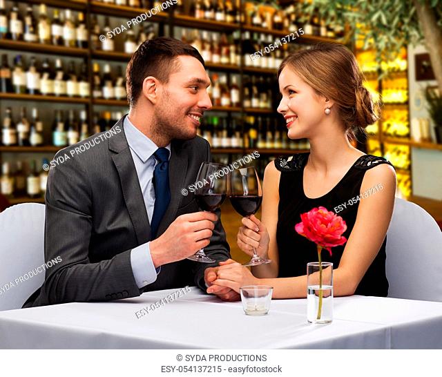 happy couple drinking red wine at restaurant