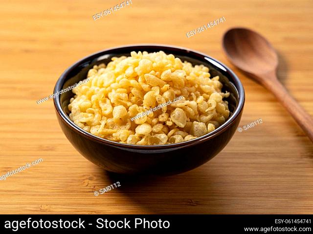 Tenkasu and wooden spoon served in a bowl placed on a wooden background. Image of Japanese food