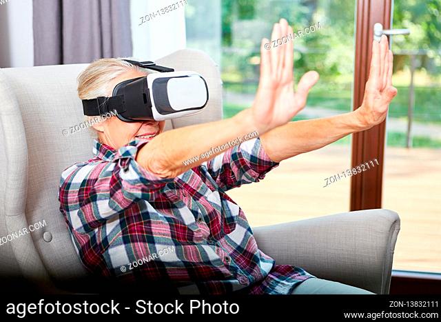 Senior Frau mit VR Brille beim Tasten mit den Händen im Cyberspace