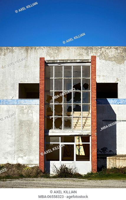 Old warehouse with red brick wall and smashed windows