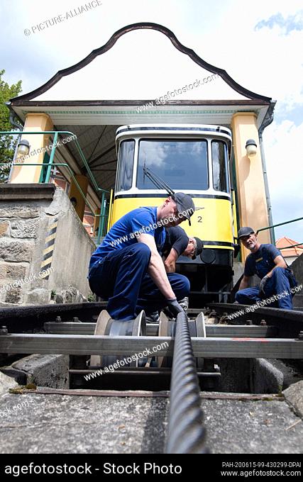 15 June 2020, Saxony, Dresden: Technicians from the Dresden Transport Authority (DVB) are working on a cable pulley in front of a funicular railway car at the...