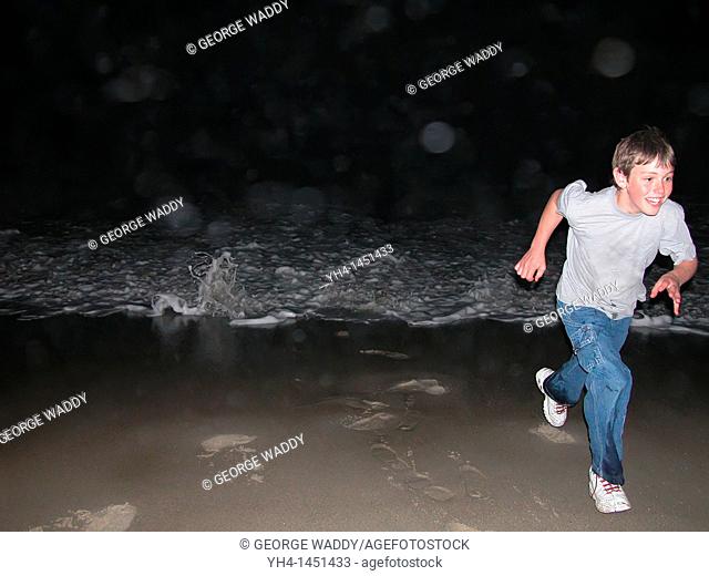 Young Boy running from wave