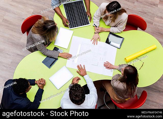 High angle view of business colleagues having a meeting with plan, wireless devices and solar panel on table