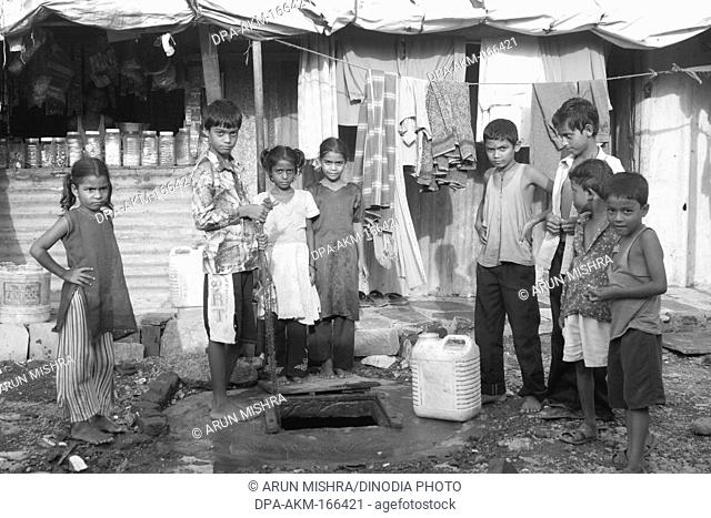 Children stand front of bore well in Malvani slum ; Malad ; Bombay Mumbai ; Maharashtra ; India