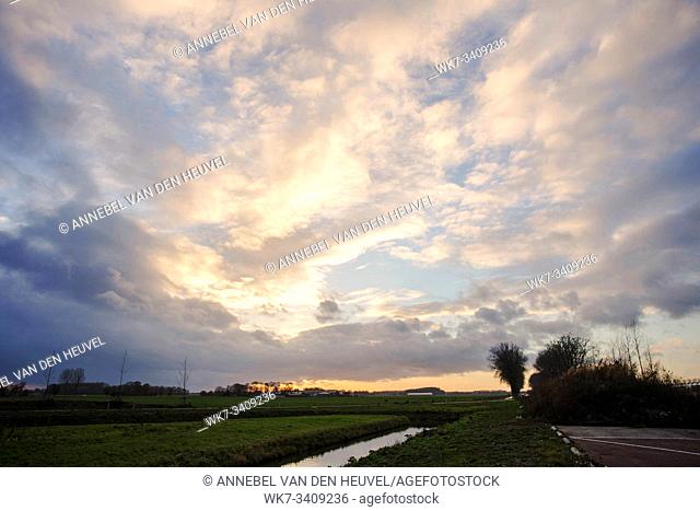 Natural Sunset Sunrise Over Field Or Meadow. Bright Dramatic Sky And Dark Ground. Countryside Landscape Under Scenic Colorful Sky At Sunset Dawn Sunrise