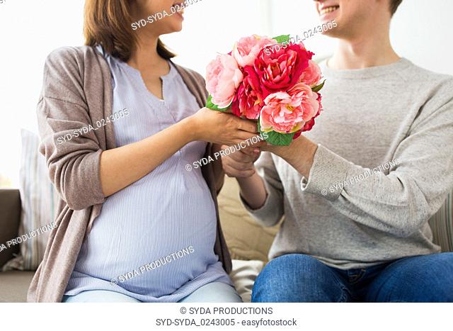 close up of man giving flowers to pregnant wife