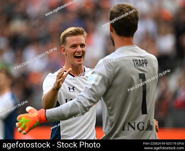 24 August 2022, Hessen, Frankfurt/Main: Mick Schumacher (l) and Kevin Trapp greet each other on the pitch at the ""Champions for Charity"" charity match in...