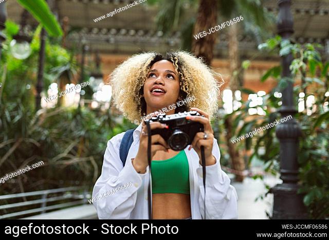 Young woman looking up holding camera