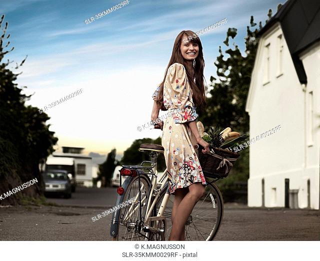 Woman pushing bicycle along rural road