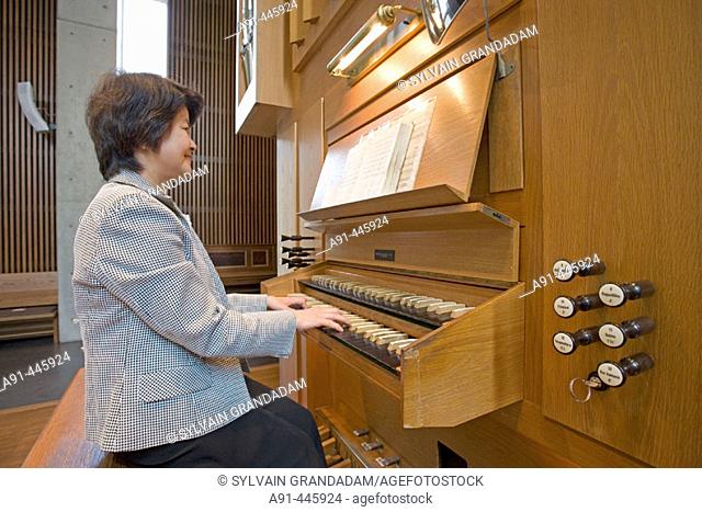 Organ player. Shinto family celebrating the anniversary of the mother's death in a protestant temple. The Shubuya quarter.Tokyo. Japan