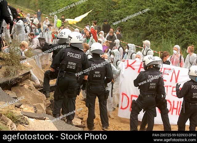 25 July 2020, North Rhine-Westphalia, Keyenberg: Environmental activists in white overalls climb over a wall to enter the Garzweiler open-cast mine and are...