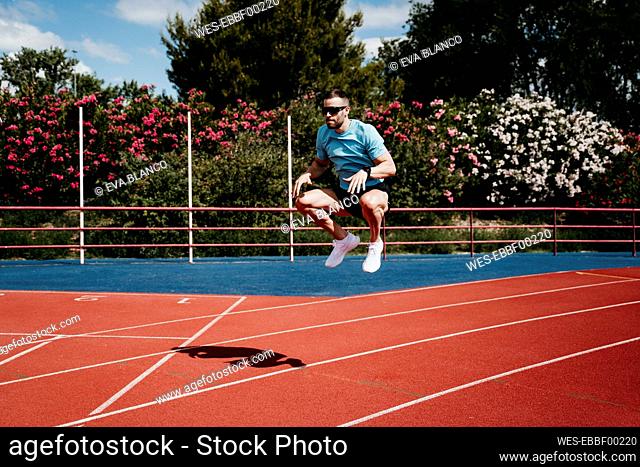 Male athlete jumping on tartan track