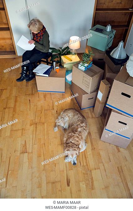 Senior woman looking at papers surrounded by cardboard boxes in an empty room