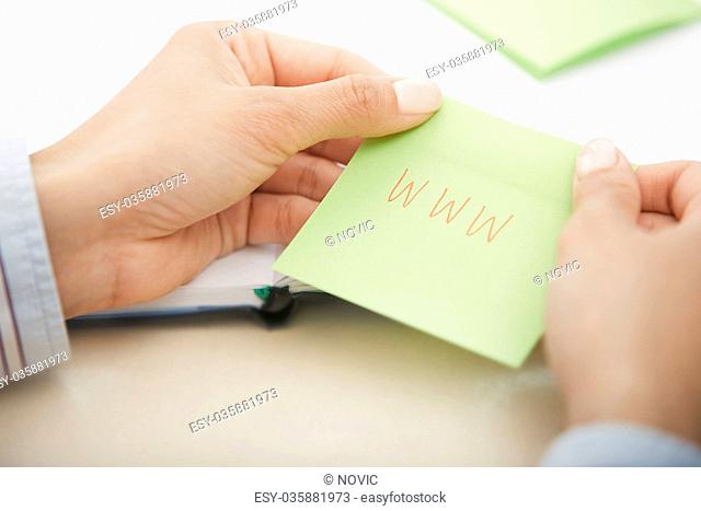 Hands holding sticky note with internet address
