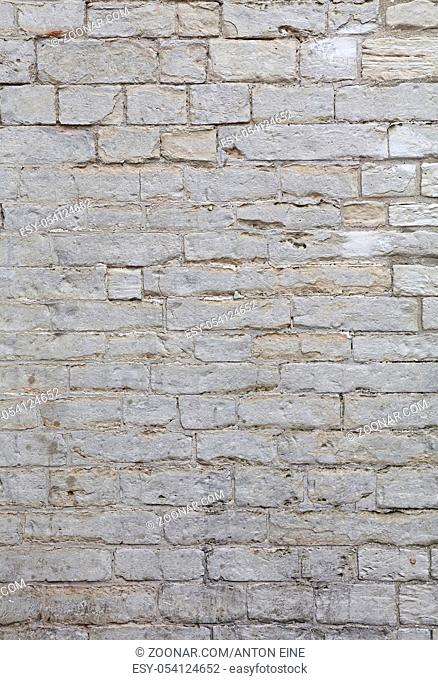 Wall of white and gray weathered limestone travertine stone brick blocks, close up background texture, side view