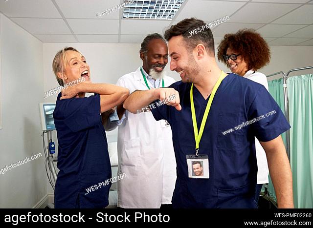 Playful medical colleagues giving elbow bump in medical room