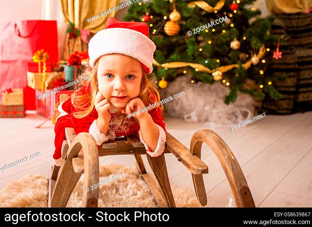 Little child in christmas hat dreaming about christmas miracle. Girl makes a wish an new year night
