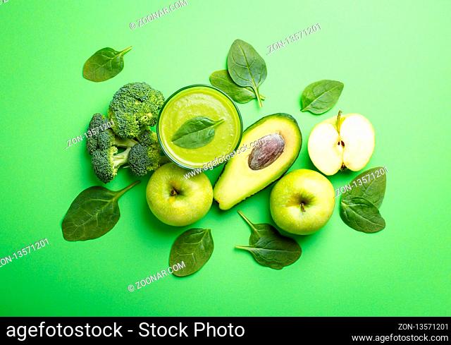 Ingredients for making green healthy smoothie with broccoli, apples, avocado, spinach on green pastel background. Clean eating, detox plan, diet