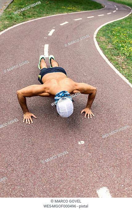 Athletic young man doing pushups in the park