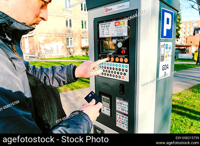 man pays for parking with a credit card with NFS technology. Easy payment. Process of paying in machine parking terminal