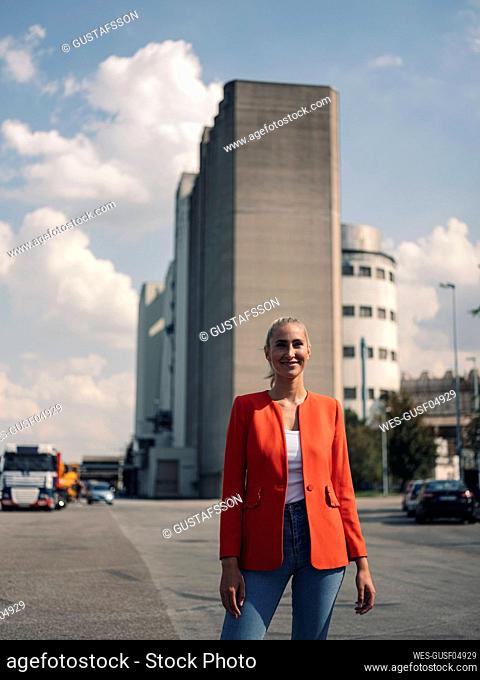 Happy businesswoman standing on street at industrial district