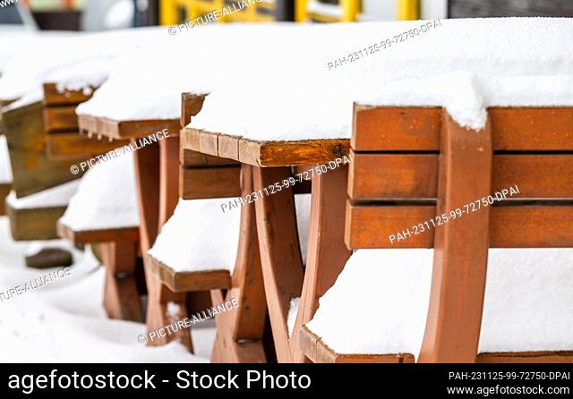 25 November 2023, Saxony, Oberwiesenthal: Tables and benches in a pub are covered in a layer of snow. There was fresh snow in the Erzgebirge during the night