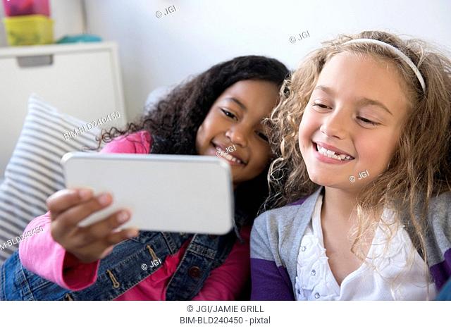Smiling girls posing for cell phone selfie