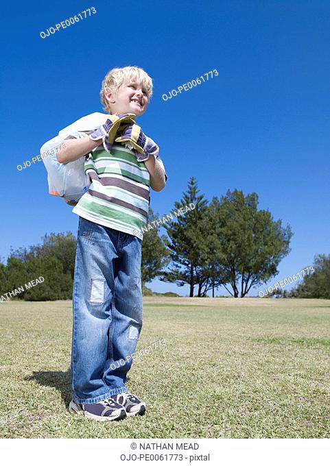 Young boy outdoors holding garbage bag