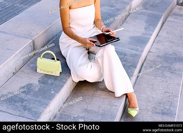 Woman using tablet PC sitting on steps
