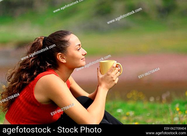 Profile of a woman drinking coffee in the mountain looking away