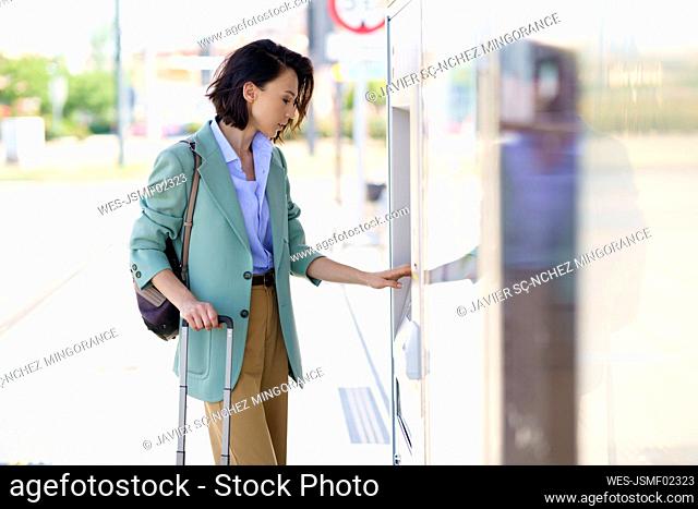 Businesswoman buying train ticket at railroad station