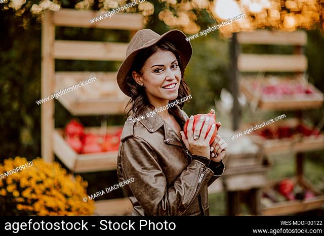 Happy woman holding pumpkin at farm