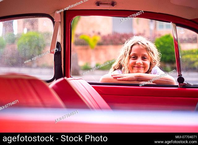 cheerful and happy young girl 8 years old smile and enjoy the day near a red vintage classic car, ready to start and travel before the school