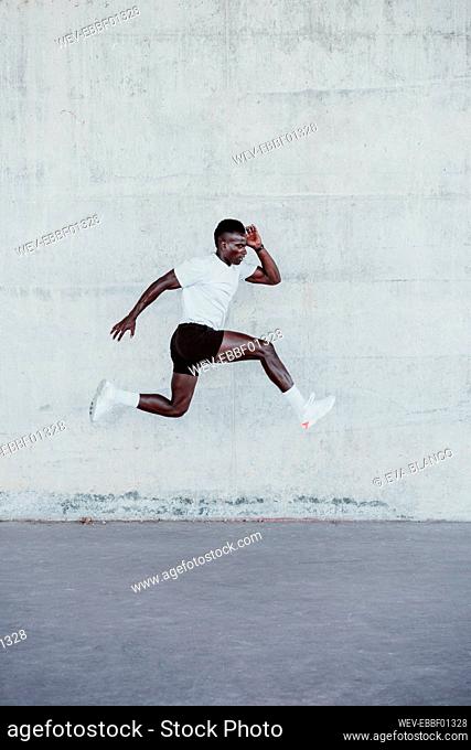 Sportsman jumping by white wall