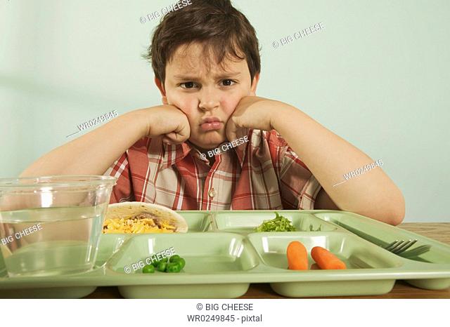 A young boy unhappy with his plate of food