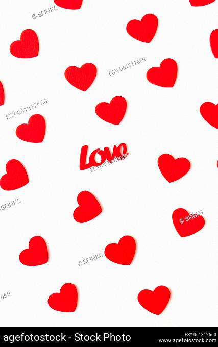 The background which consists of red hearts, the inscription love in the middle of the hearts. Vertical photo. Love concept, greeting card for valentine's day