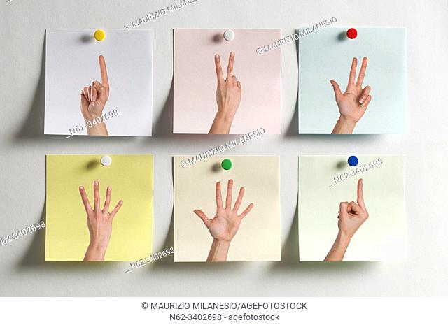 Five colorful Post It messages fixed to the wall with images of fingers indicating numbers and one with the middle finger