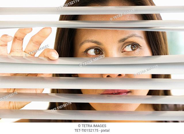 Studio shot of woman looking through blinds