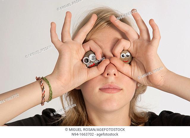 Blonde girl holding her hands in the shape of a pair of binoculars in front of her eyes