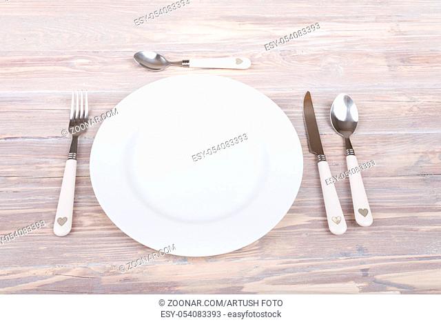 empty plate with knife and fork on empty retro vintage wooden table