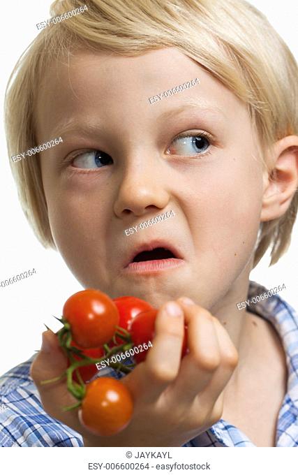 A funny boy holding a bunch of vine ripened organic cherry tomatoes and pulling a face. Isolated on white