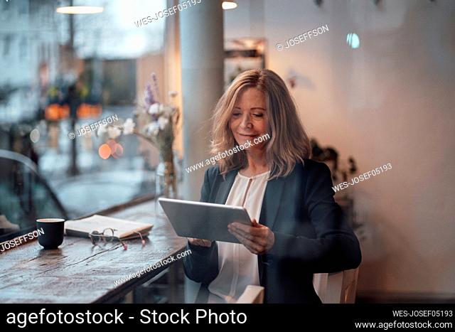 Female professional using digital tablet sitting in cafe