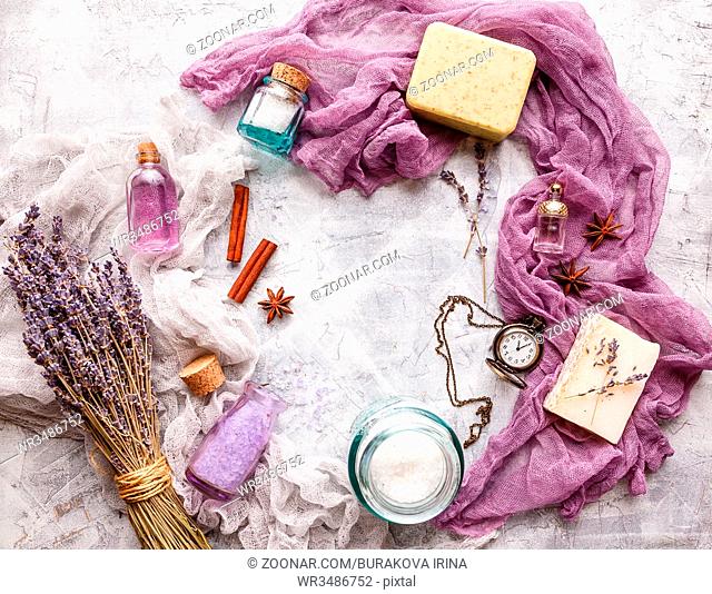Lavender background with bouquet and twigs of dry lavender, bottle with cosmetic oil, perfume bottle, soap, vintage pocket watch, cinnamon sticks